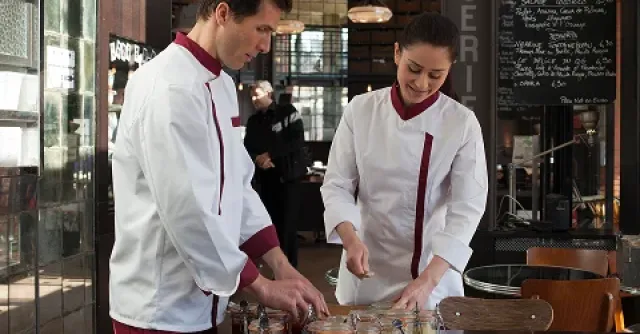 Deux personnes en tenu de service, manipulant des bocaux