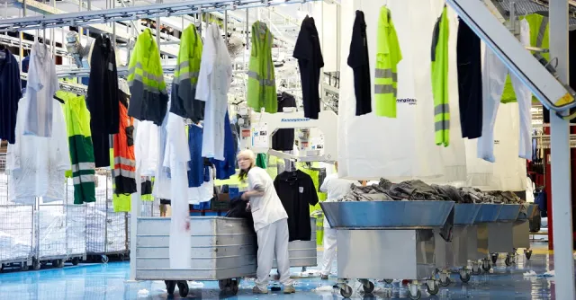Personne poussant un chariot, devant elle des tenues sur une ligne